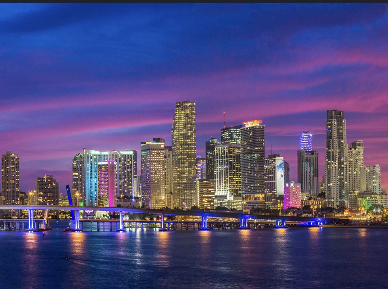Skyline del downtown de Miami iluminado al anochecer, visto desde la Bahía Biscayne